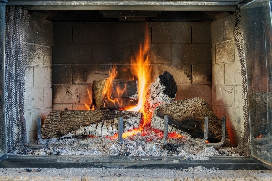 Active fireplace with burning logs and ash in hearth