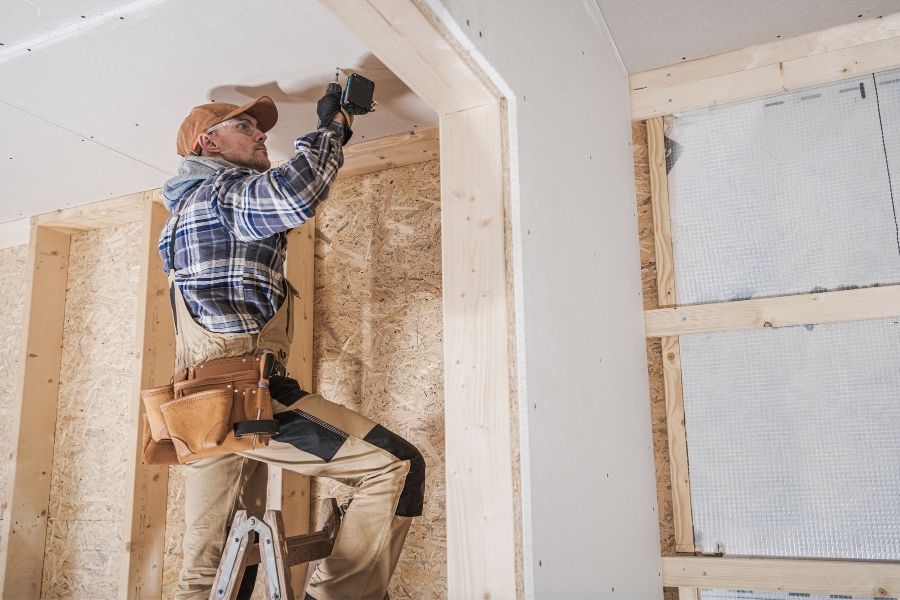 Drywall installer working on ceiling during reconstruction