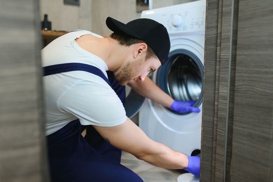 Technician inspecting front-load washing machine for potential issues