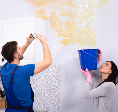 An expert from FFF's Team inspects water damage while a colleague holds a bucket, in Lady Lake,FL