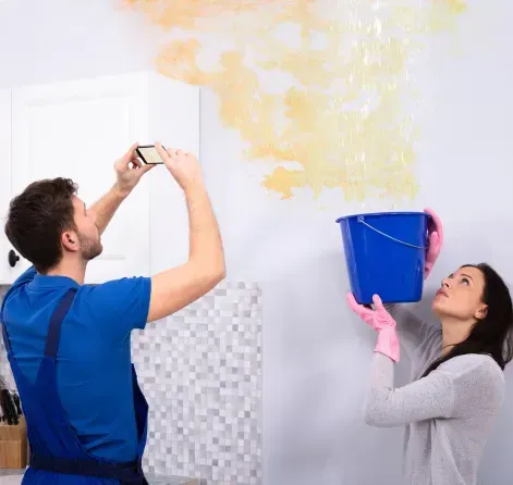 An expert from FFF's Team inspects water damage while a colleague holds a bucket in Sanford,FL