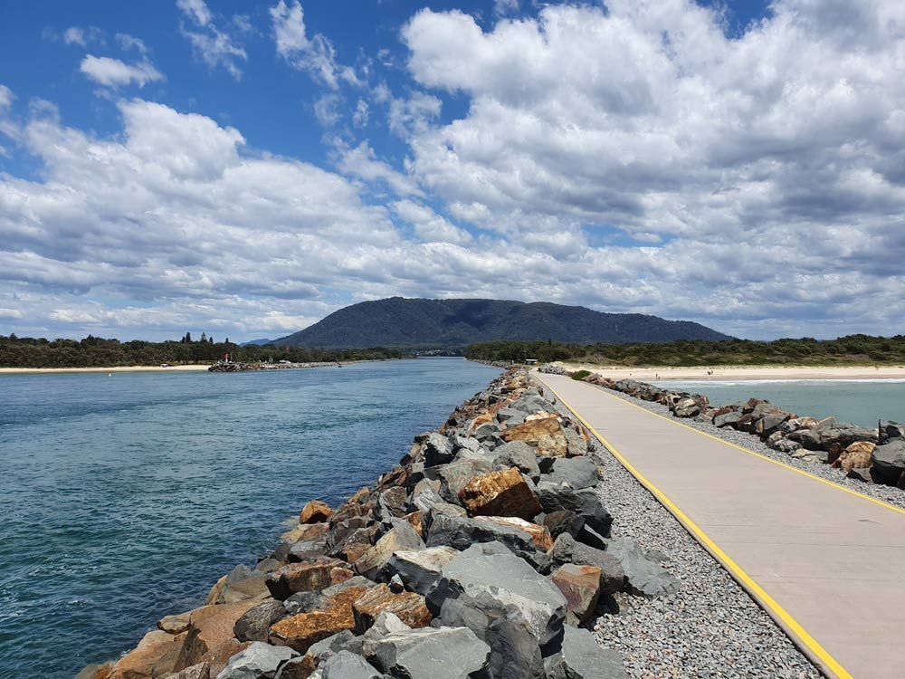 A Bridge Over A Body Of Water With A Mountain In The Background — Sunny's Skips in Laurieton, NSW