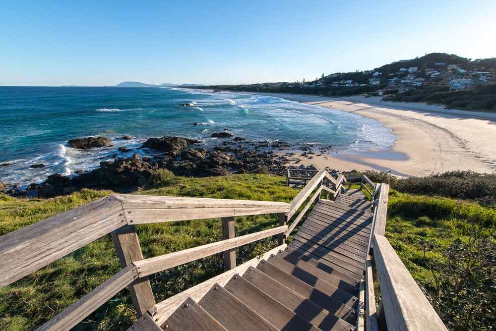 A Wooden Staircase Leading To A Beach With A View Of The Ocean — Sunny's Skips in Port Macquarie, NSW