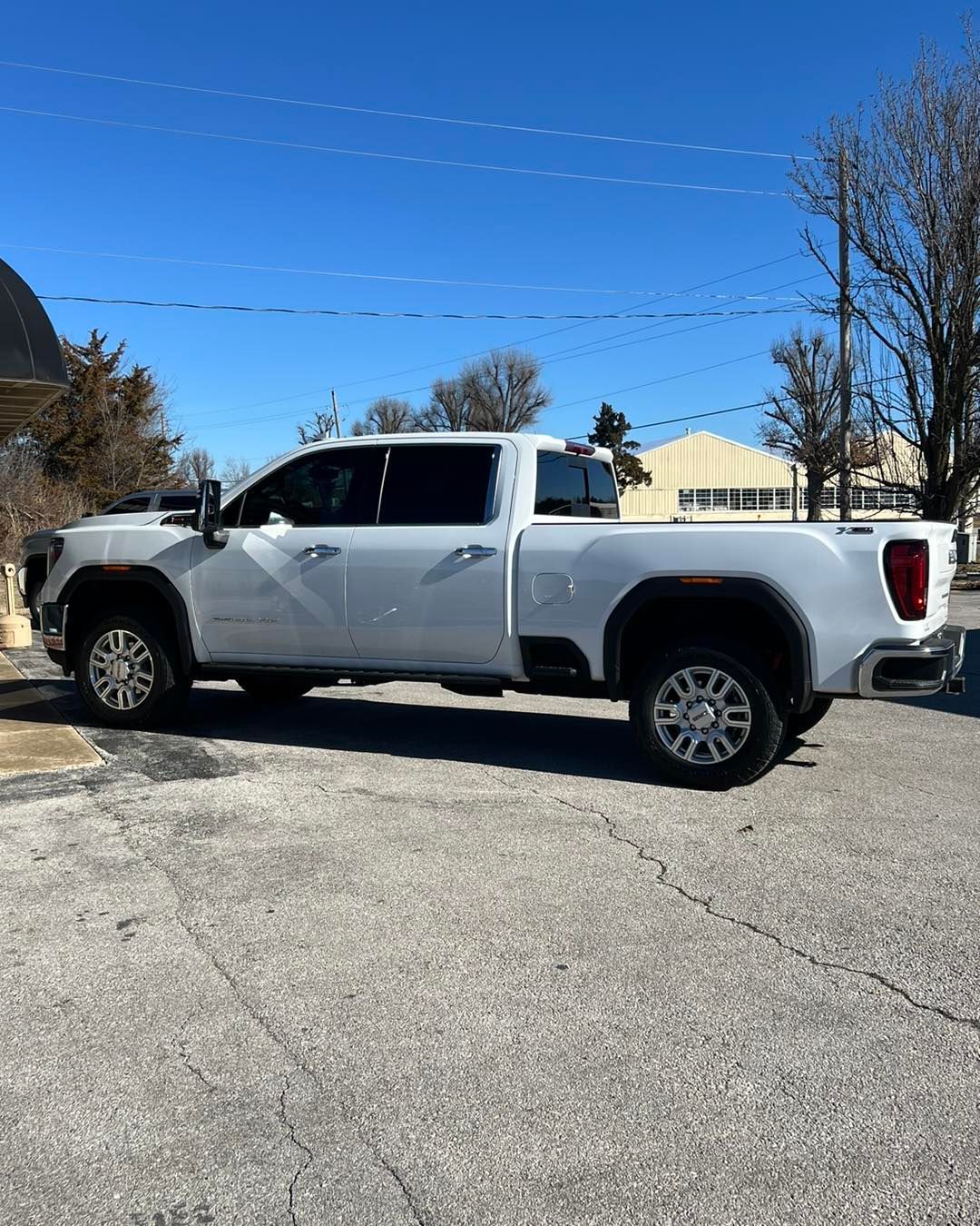 White GMC pickup truck parked on a concrete lot on a sunny day.