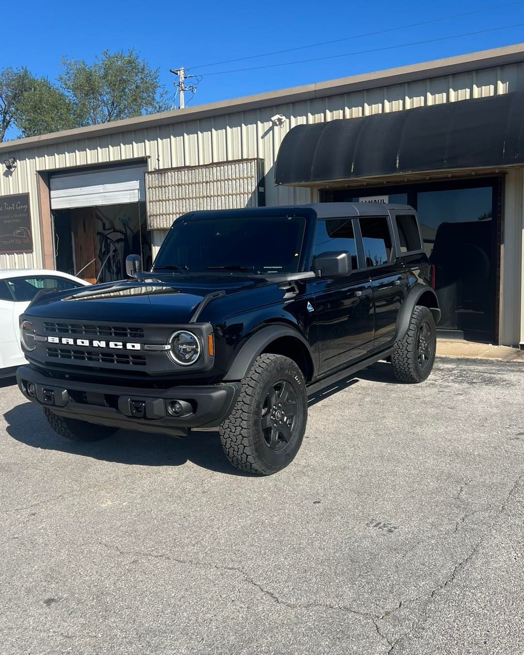 Black Ford Bronco parked in front of a building with tinted windows.