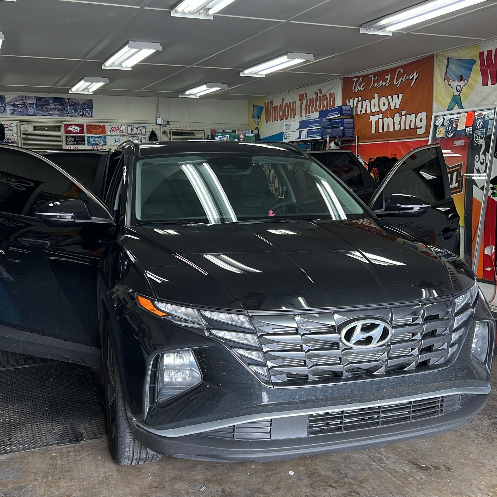 Black Hyundai Tucson SUV with tinted windows in a window tinting shop.