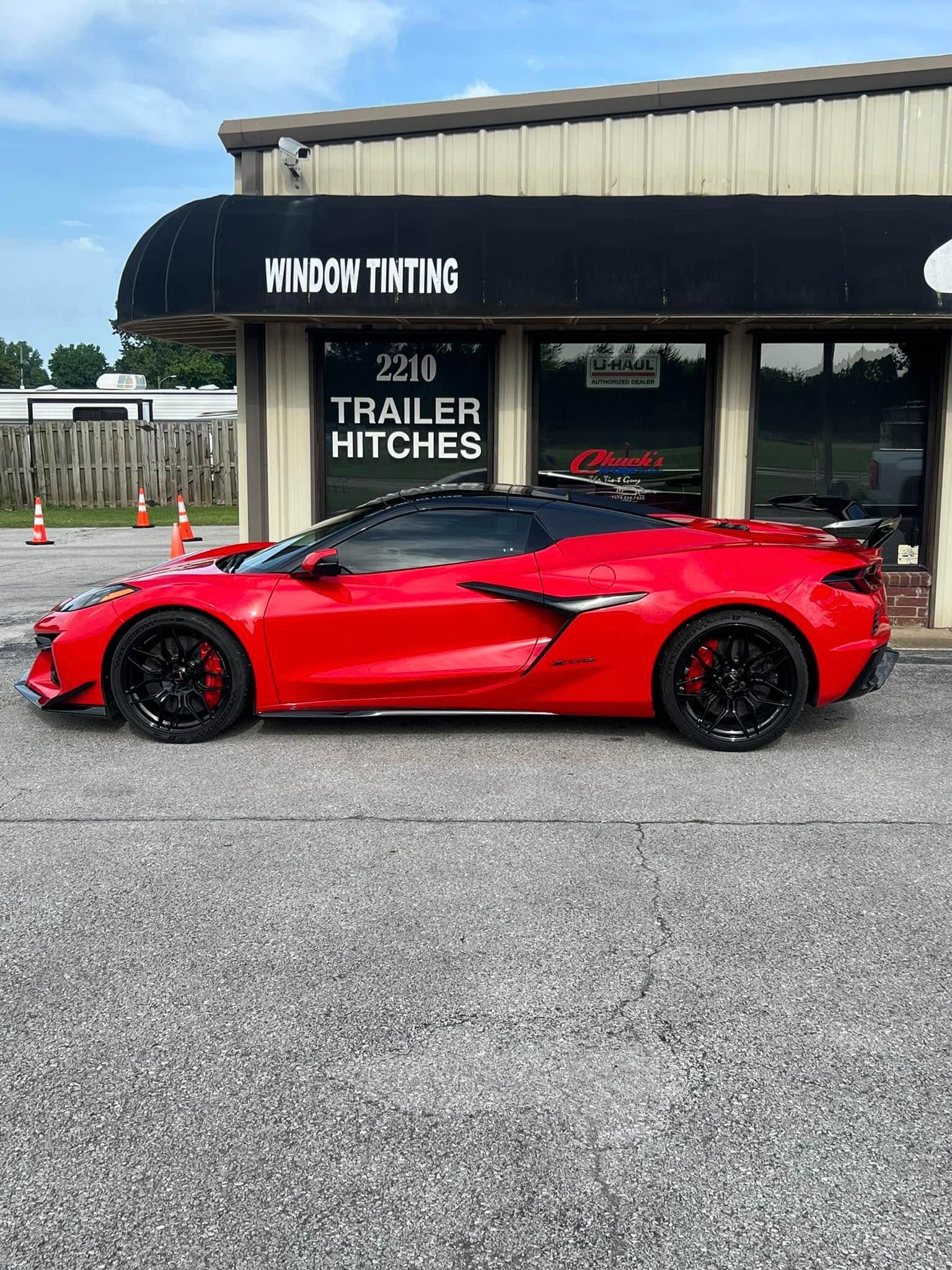 Red sports car parked outside a business with black awning.