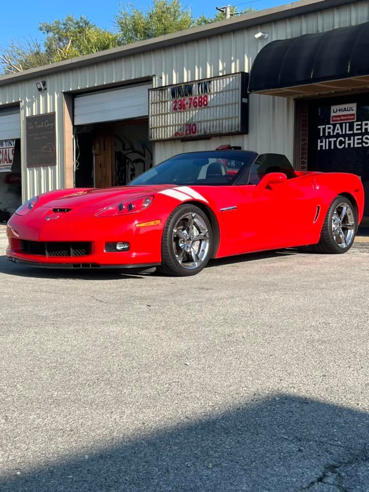 Red Corvette convertible parked outside a trailer hitch business.