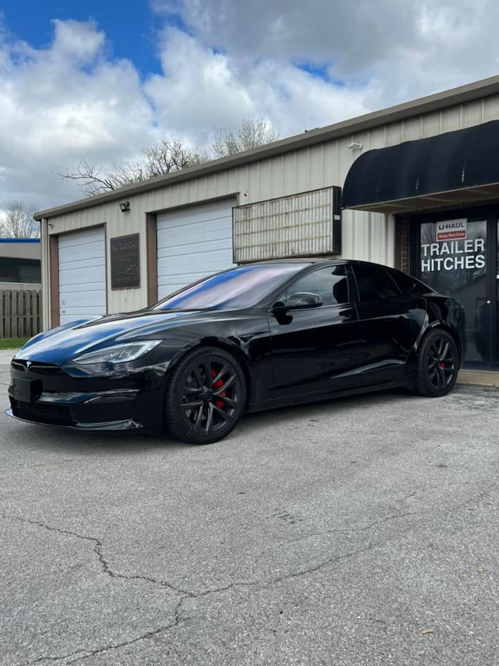 Black Tesla parked in front of a building with a 