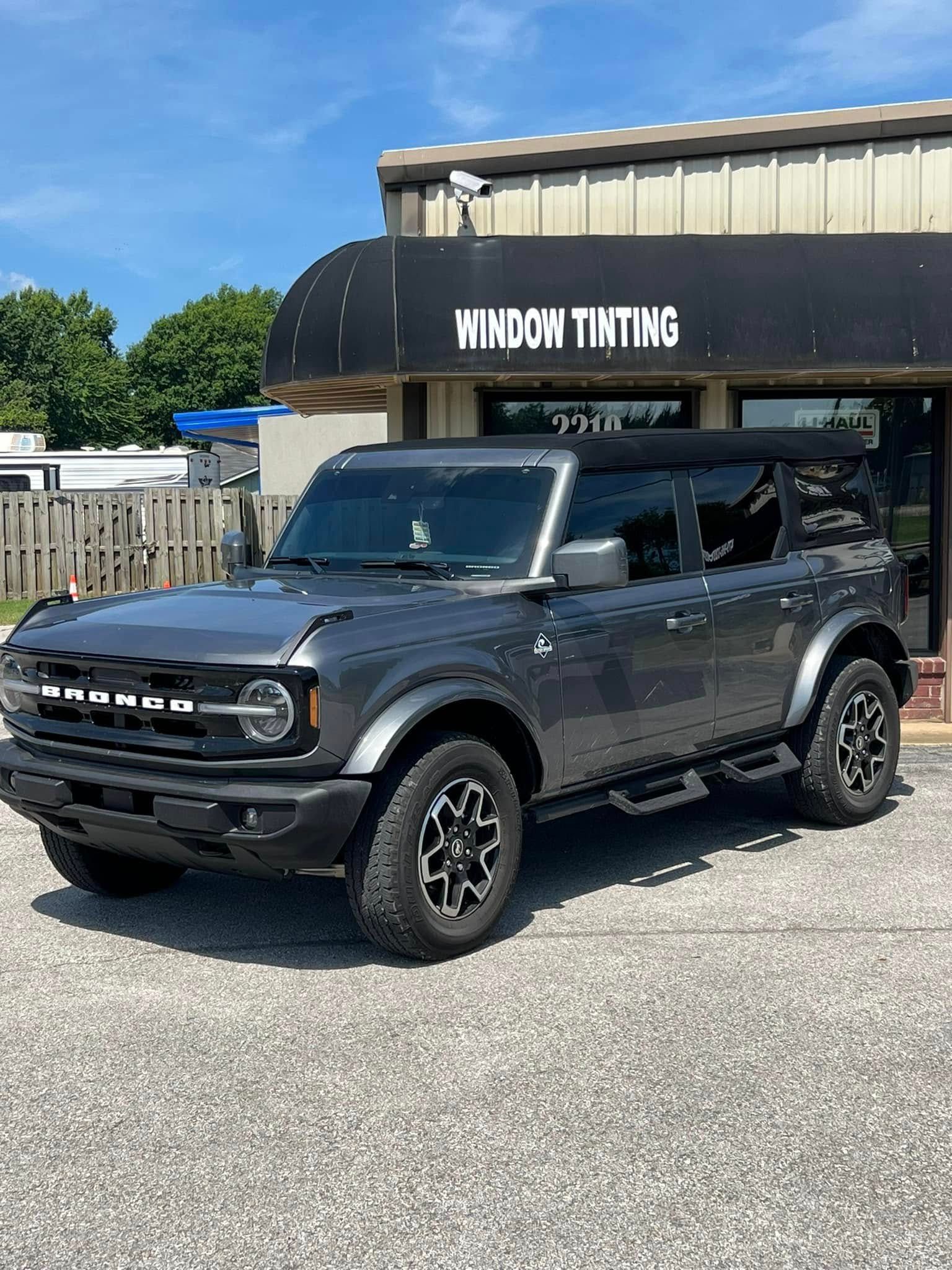 Gray Ford Bronco parked in front of a window tinting business on a sunny day.