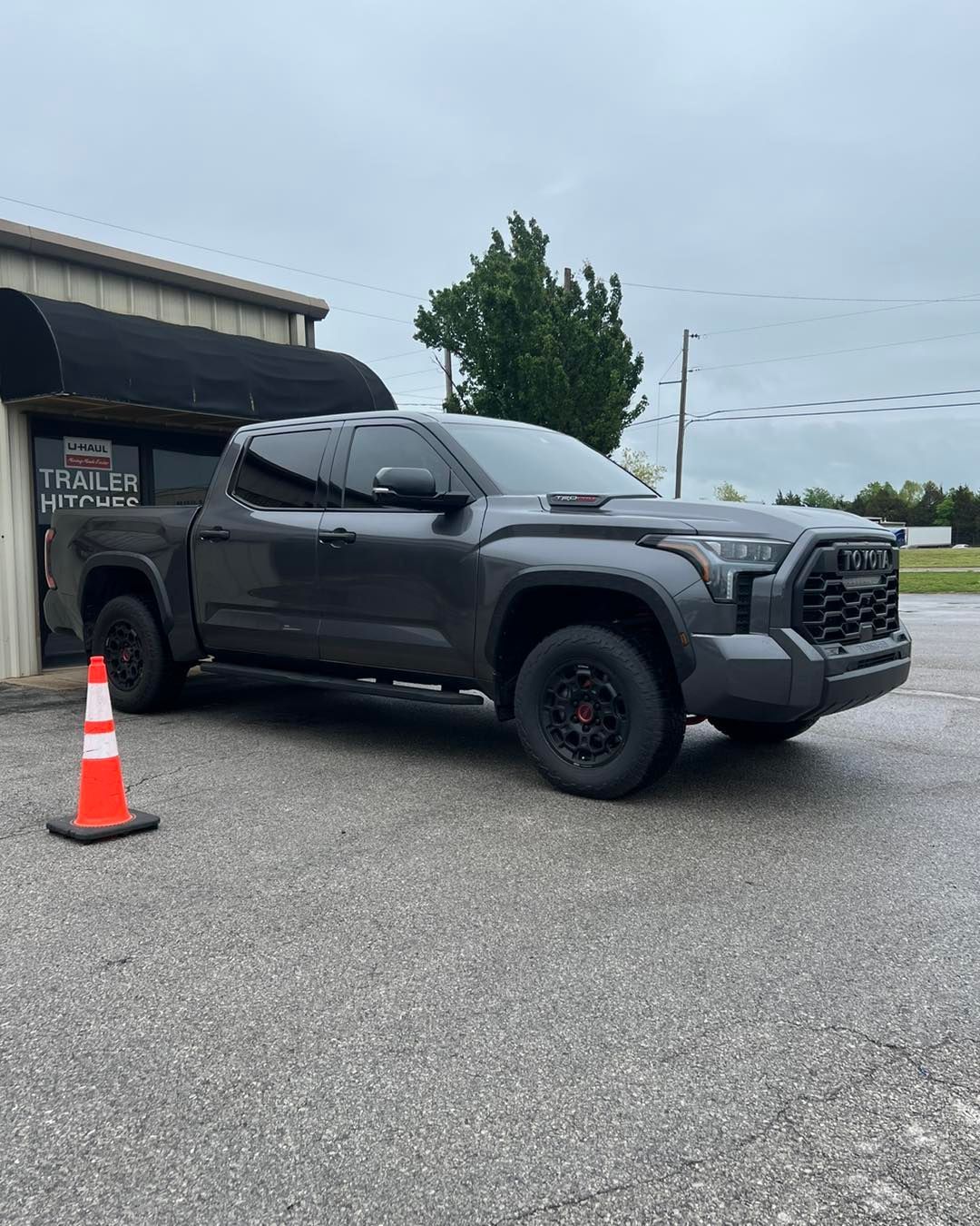 Gray Toyota Tundra pickup truck parked outside a building on a cloudy day.