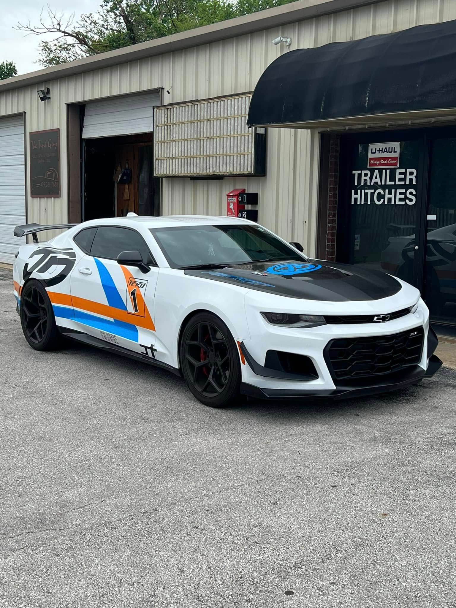 Red Chevrolet Corvette convertible on a rotating platform in a showroom.