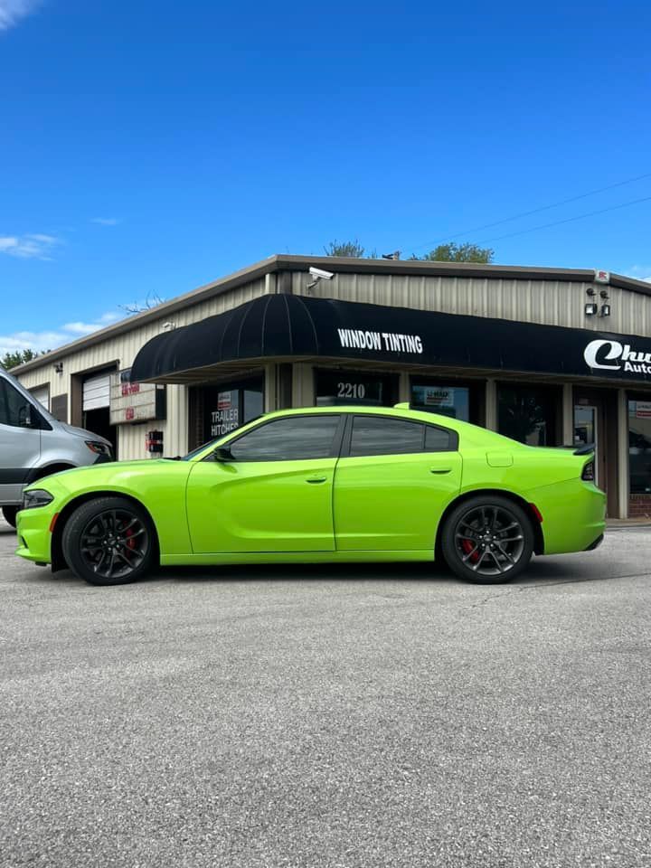 Green Dodge Charger parked in front of a building with a black awning.