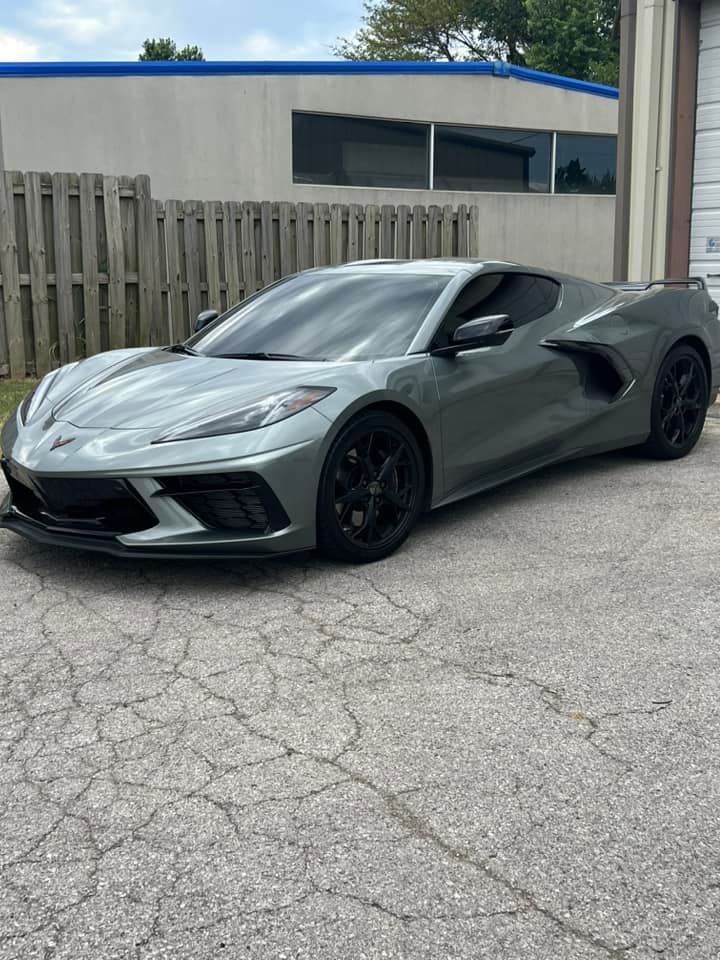 Gray Chevrolet Corvette sports car parked on cracked pavement.