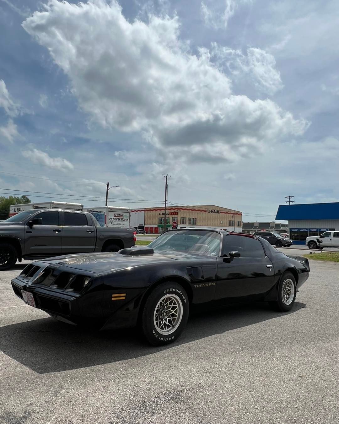 Black Pontiac Firebird Trans Am parked outside on a cloudy day.