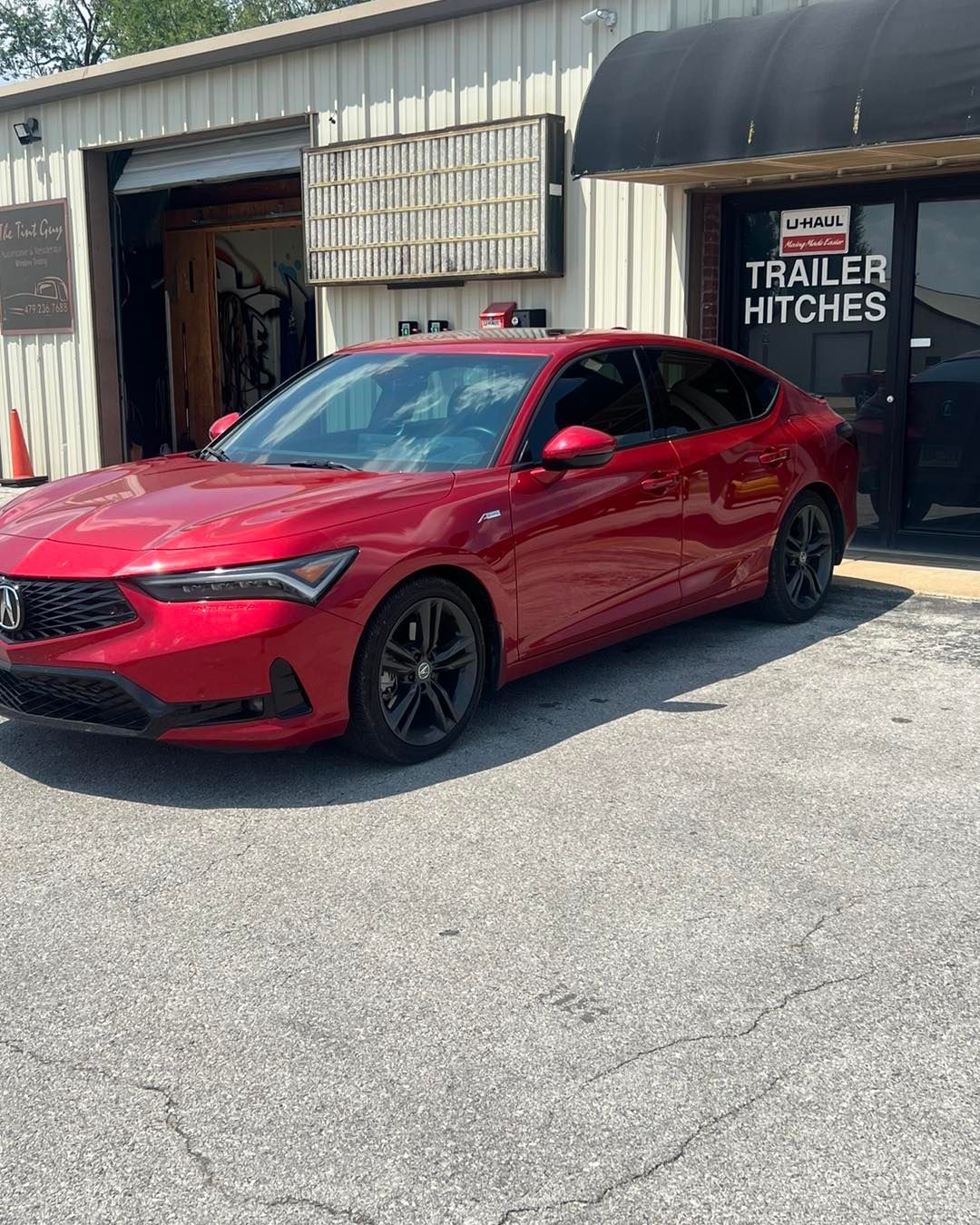 Red Acura Integra parked outside a trailer hitch business.