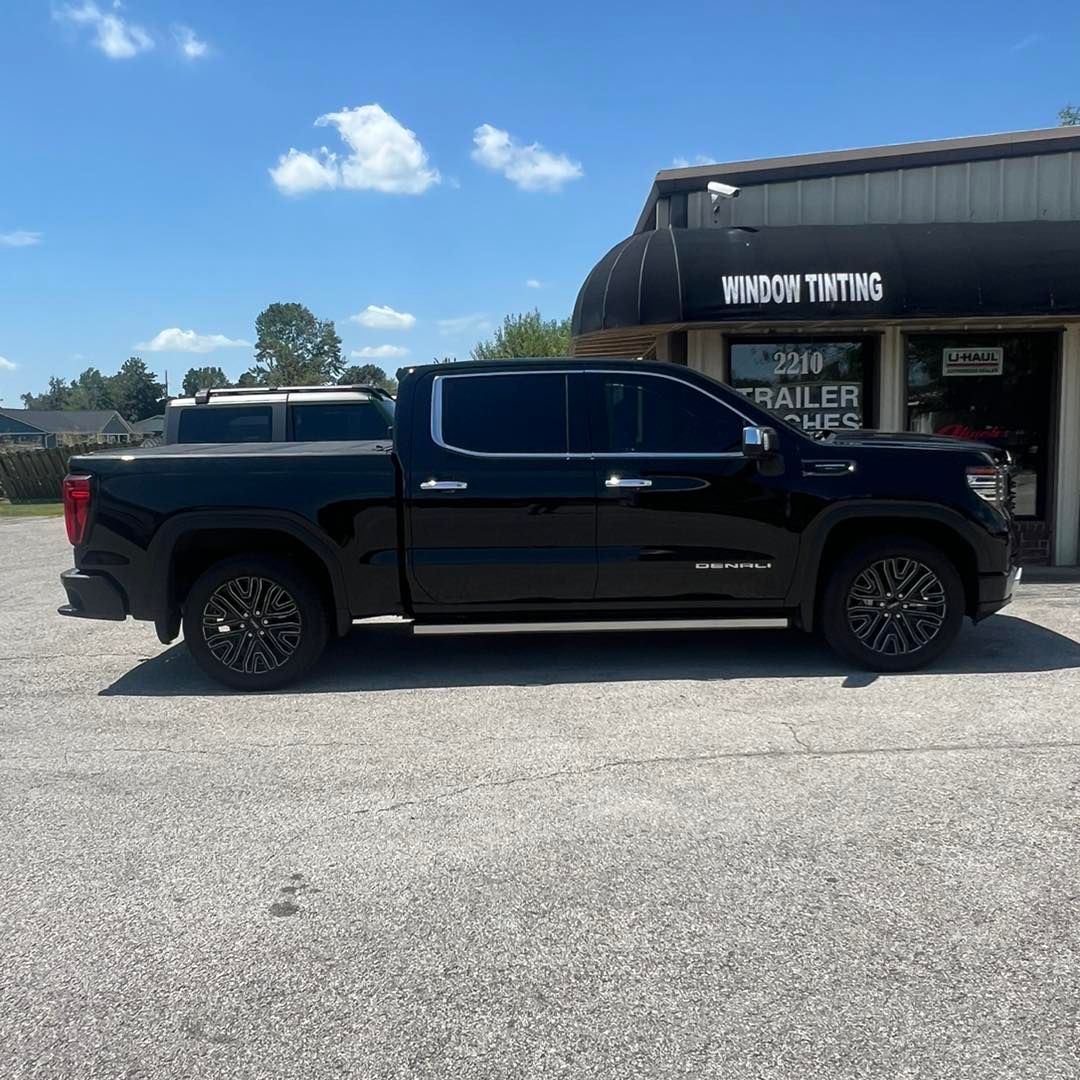 Black GMC truck parked in front of a window tinting business on a sunny day.