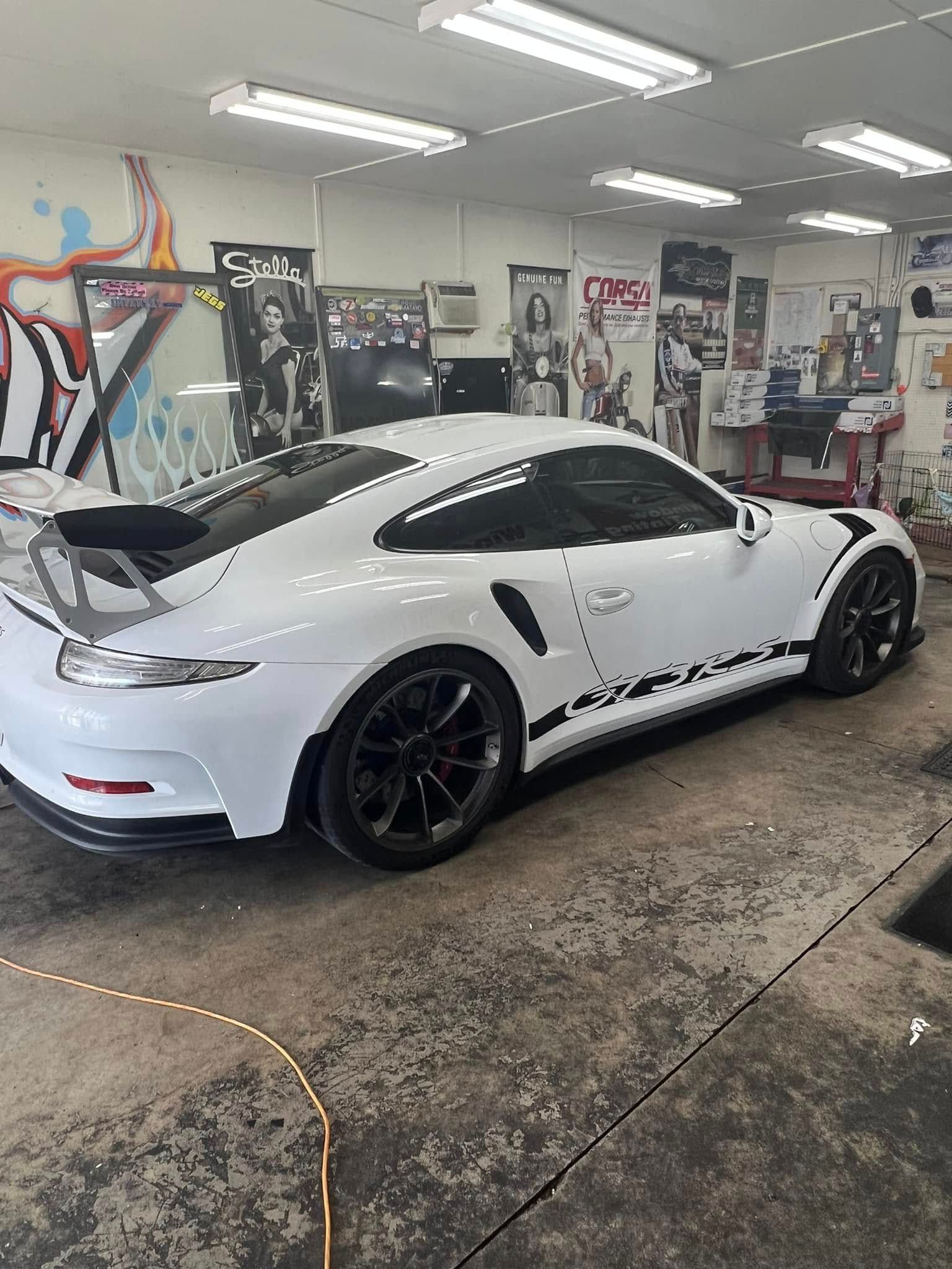 White Porsche sports car with black accents parked in a shop.