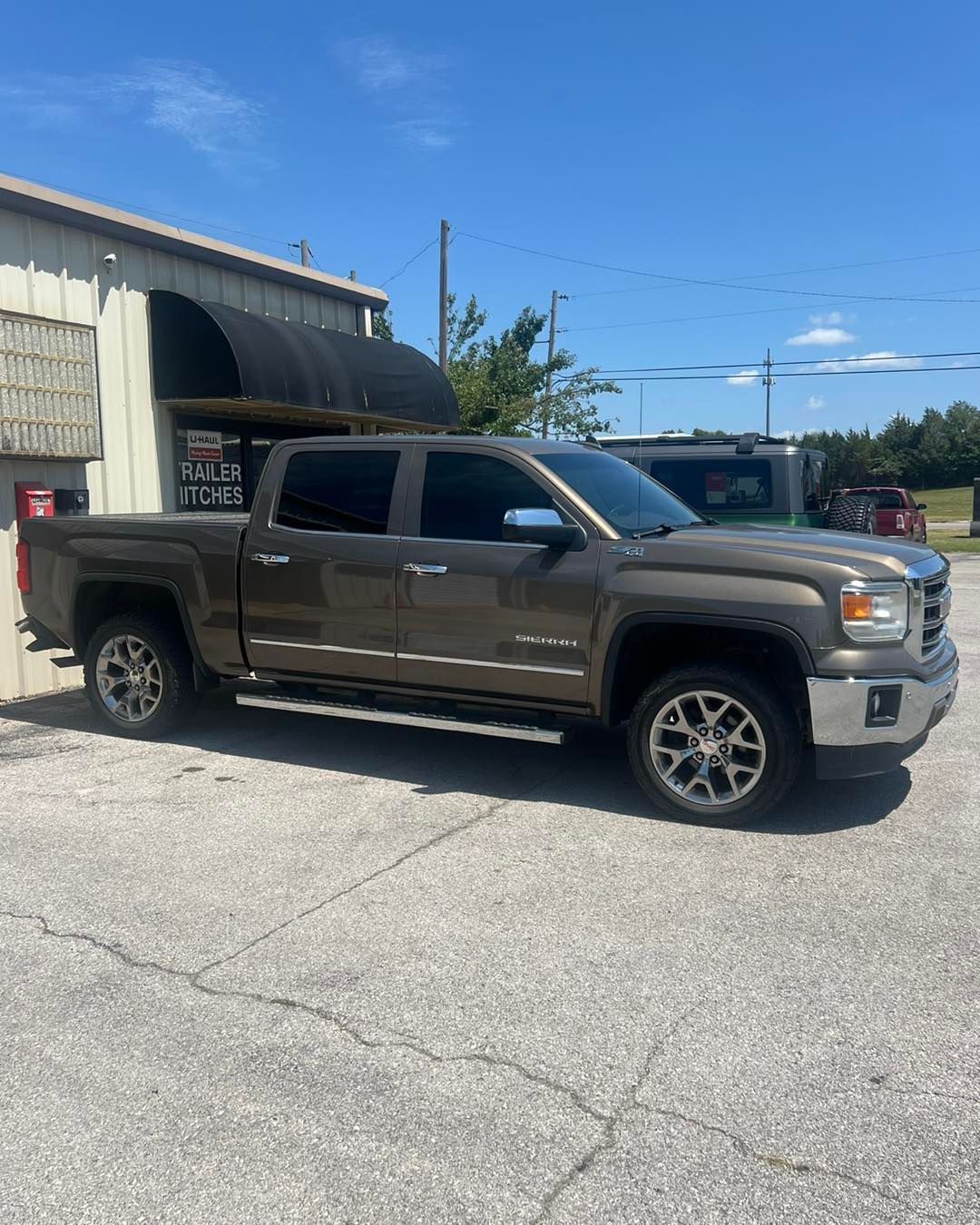 Brown GMC Sierra pickup truck parked in front of a building on a sunny day.