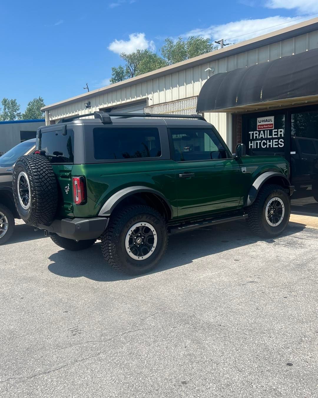 Green Ford Bronco parked outside a building with 