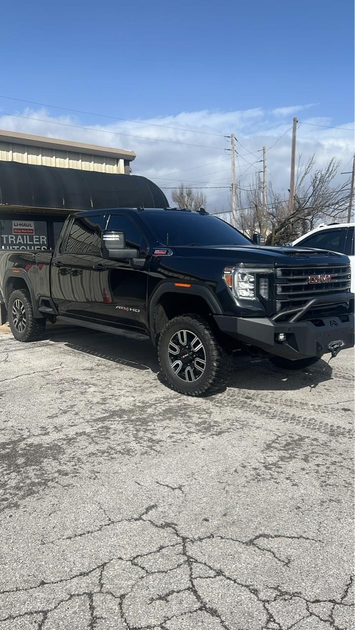 Black GMC truck parked on a paved lot on a sunny day.