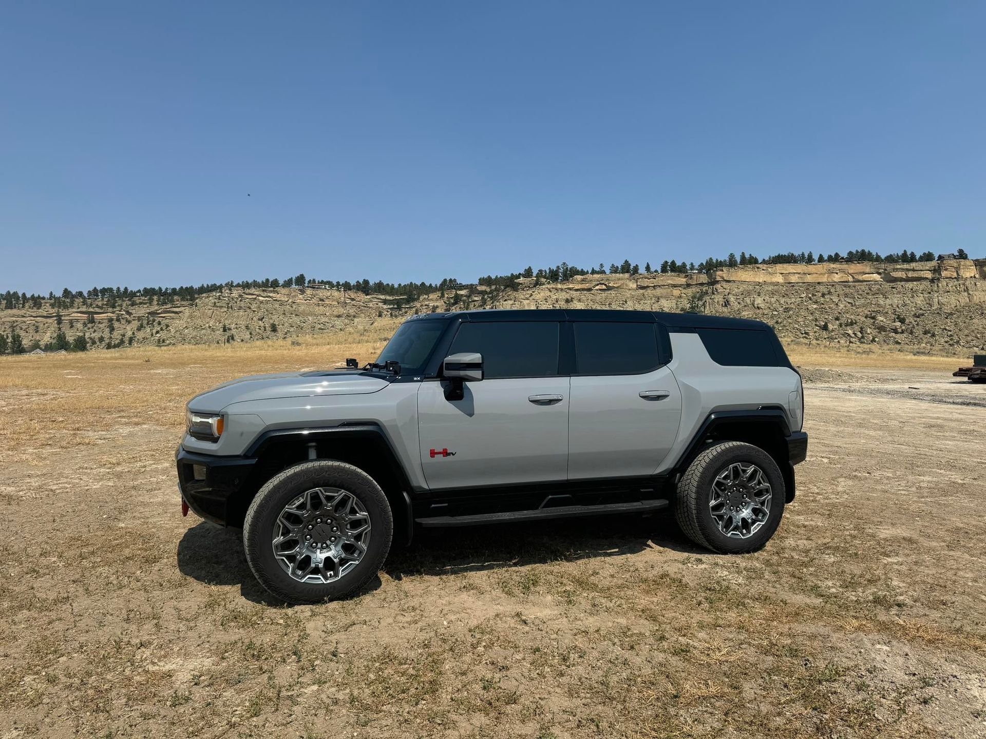 Man in blue shirt smiles behind a bar, glassware and shelves in the background.