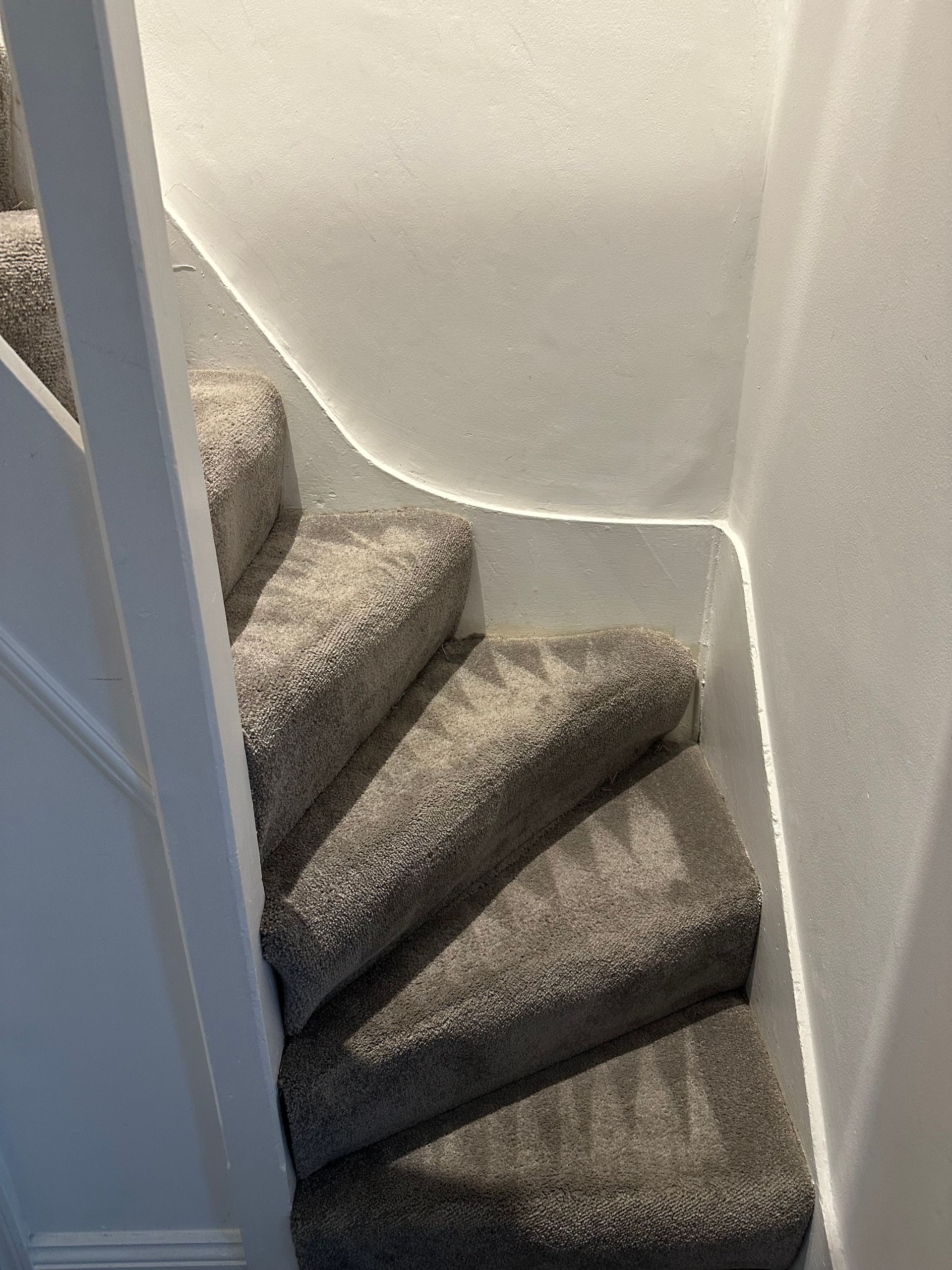 A staircase with a carpeted staircase and a white wall.