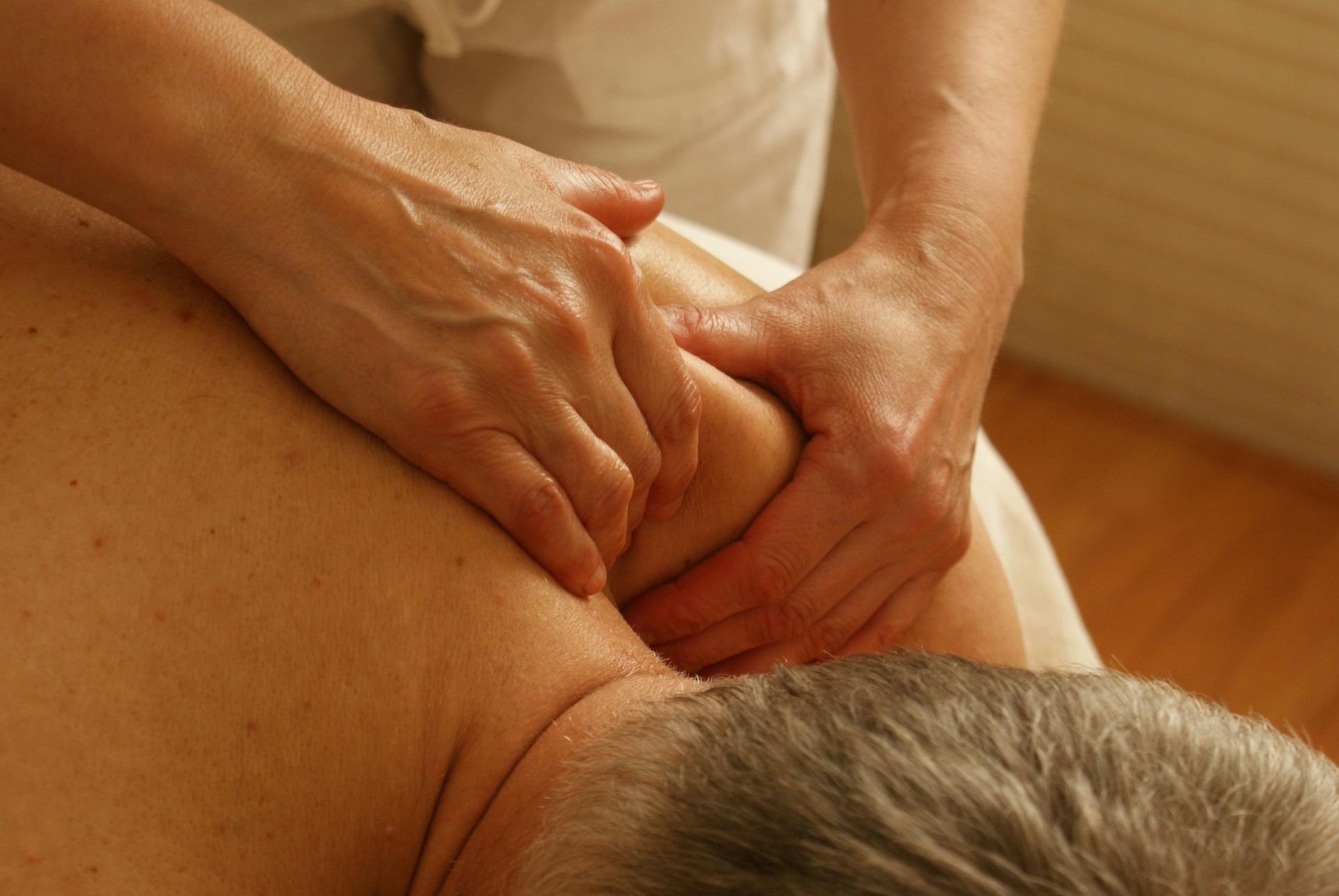 A massage therapist massaging a man's shoulder.