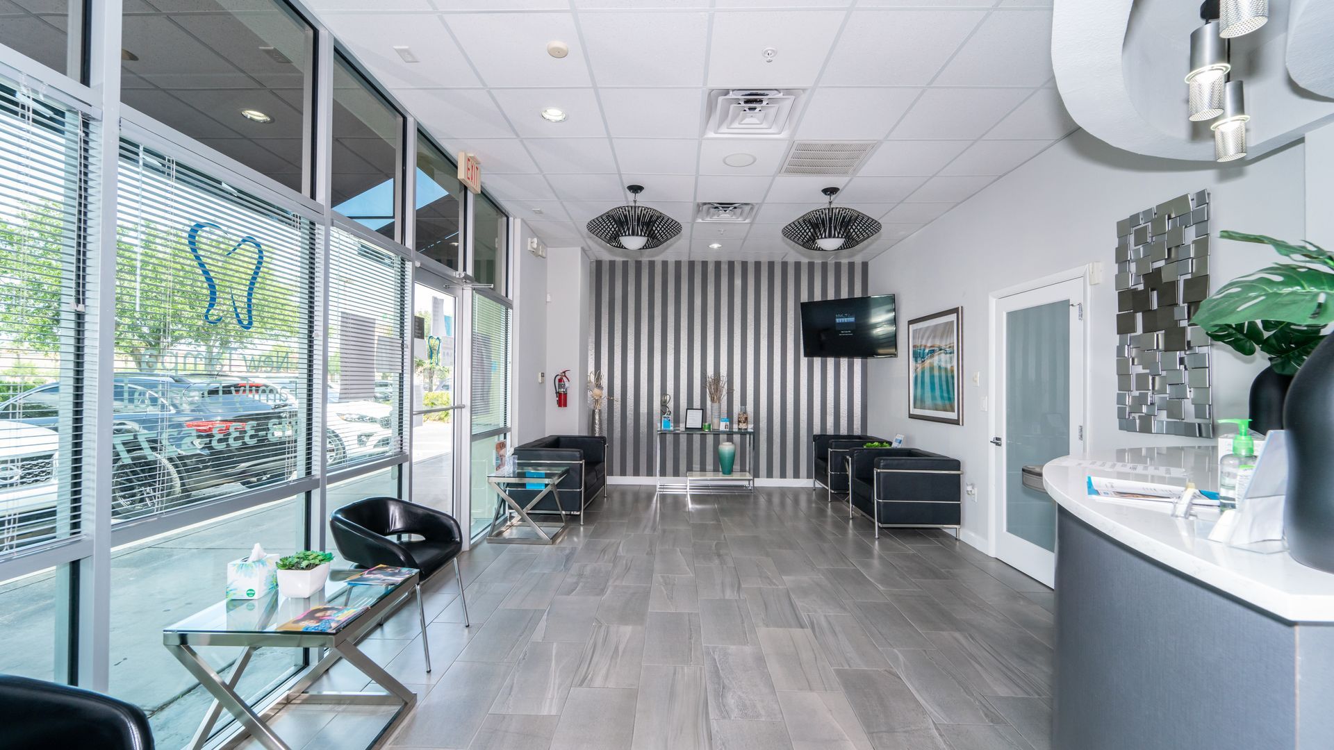 The lobby of a dental office with a lot of windows and chairs.