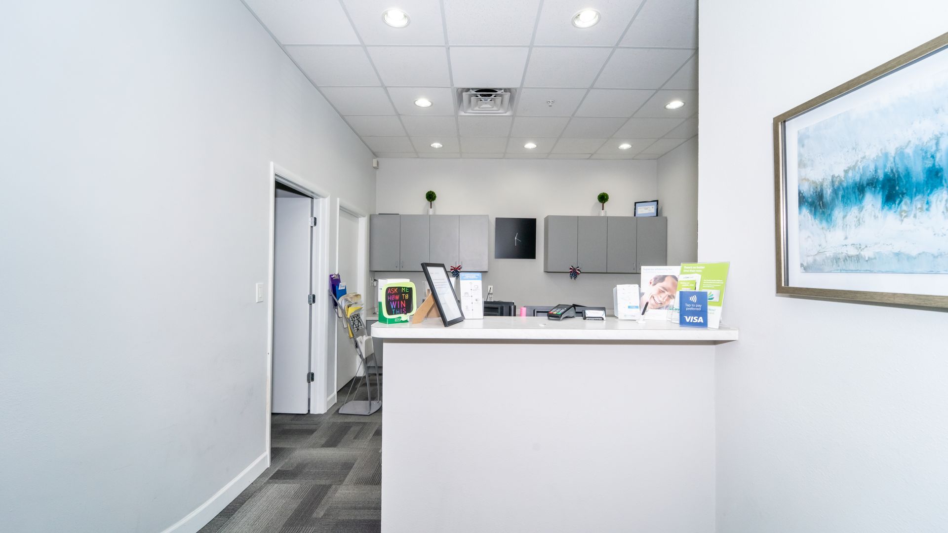 A dental office with a white counter and a painting on the wall.