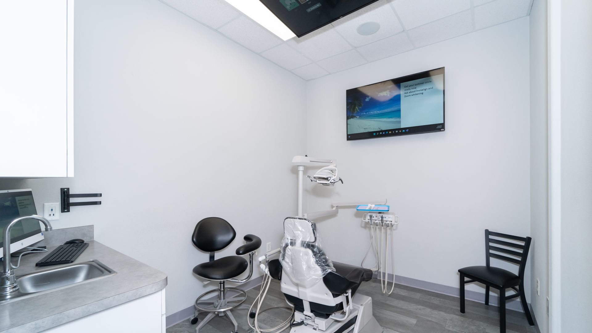 A dental office with a dental chair and a sink.