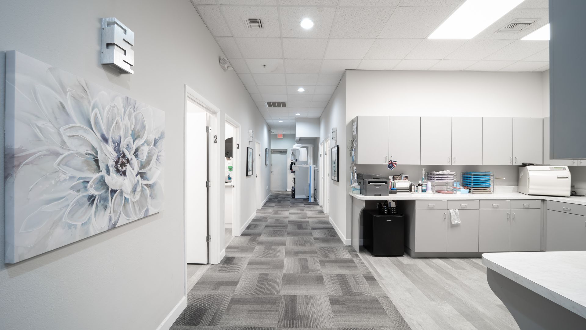 A long hallway in a hospital with a painting on the wall.