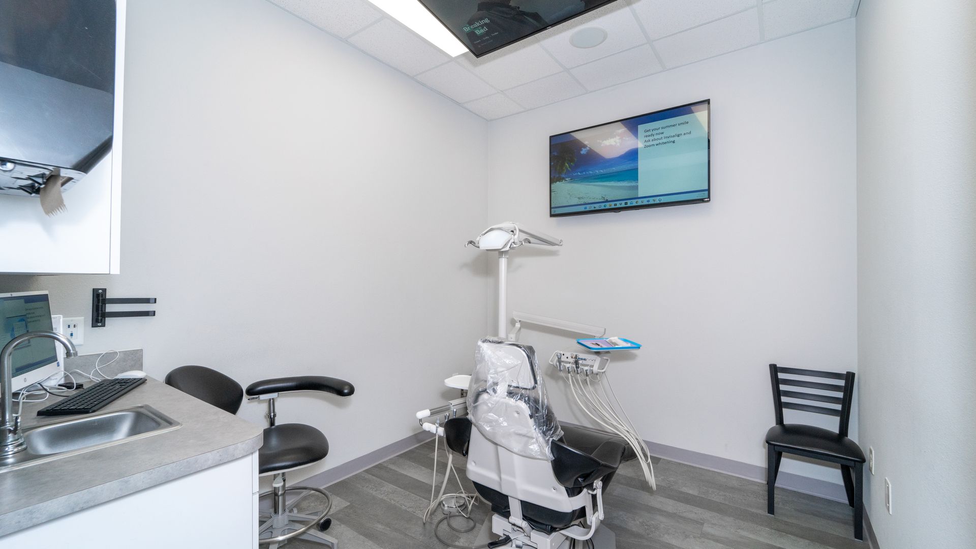 A dental office with a dental chair and a television on the wall.