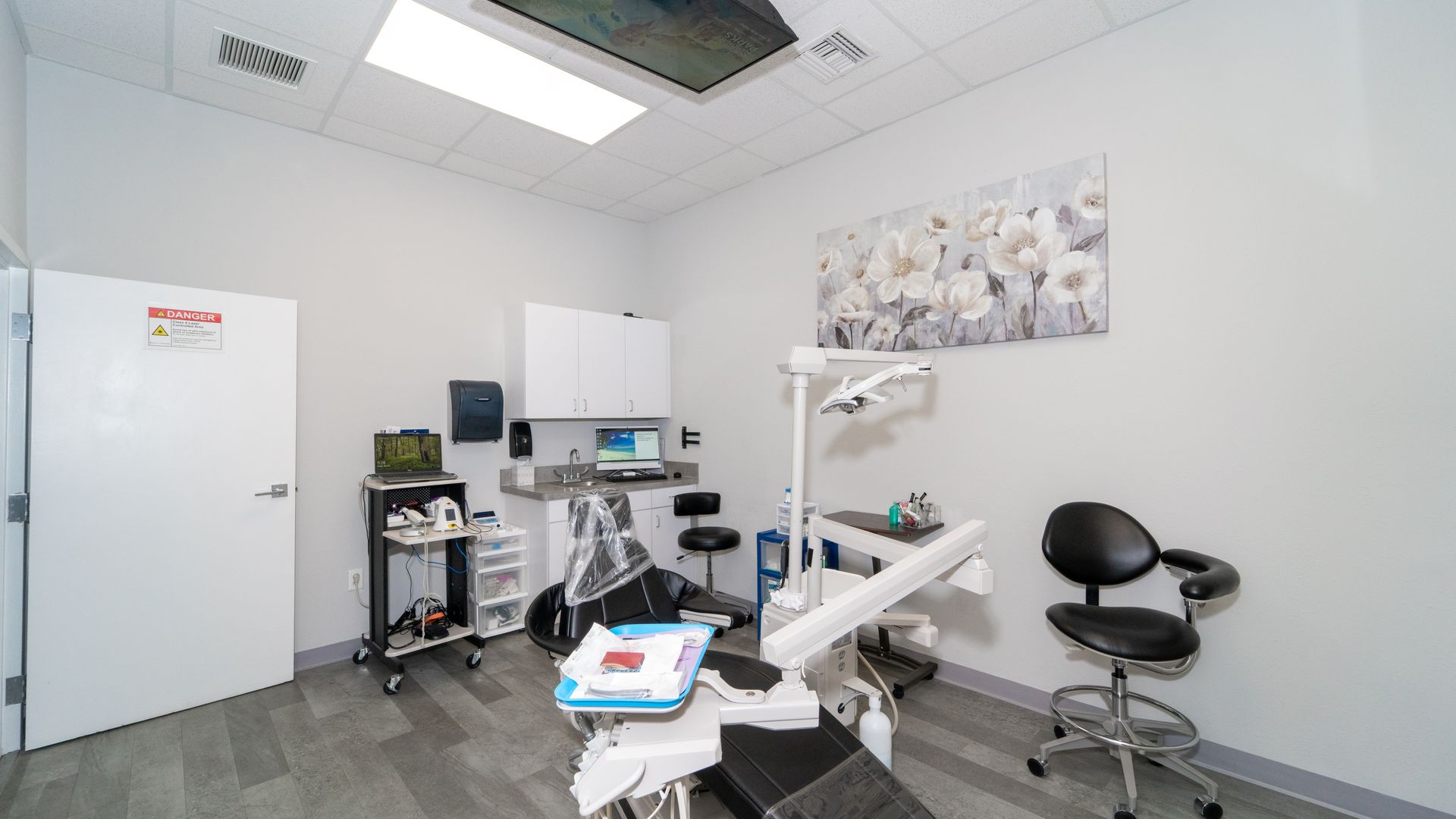 A dental office with a dental chair and a painting on the wall.