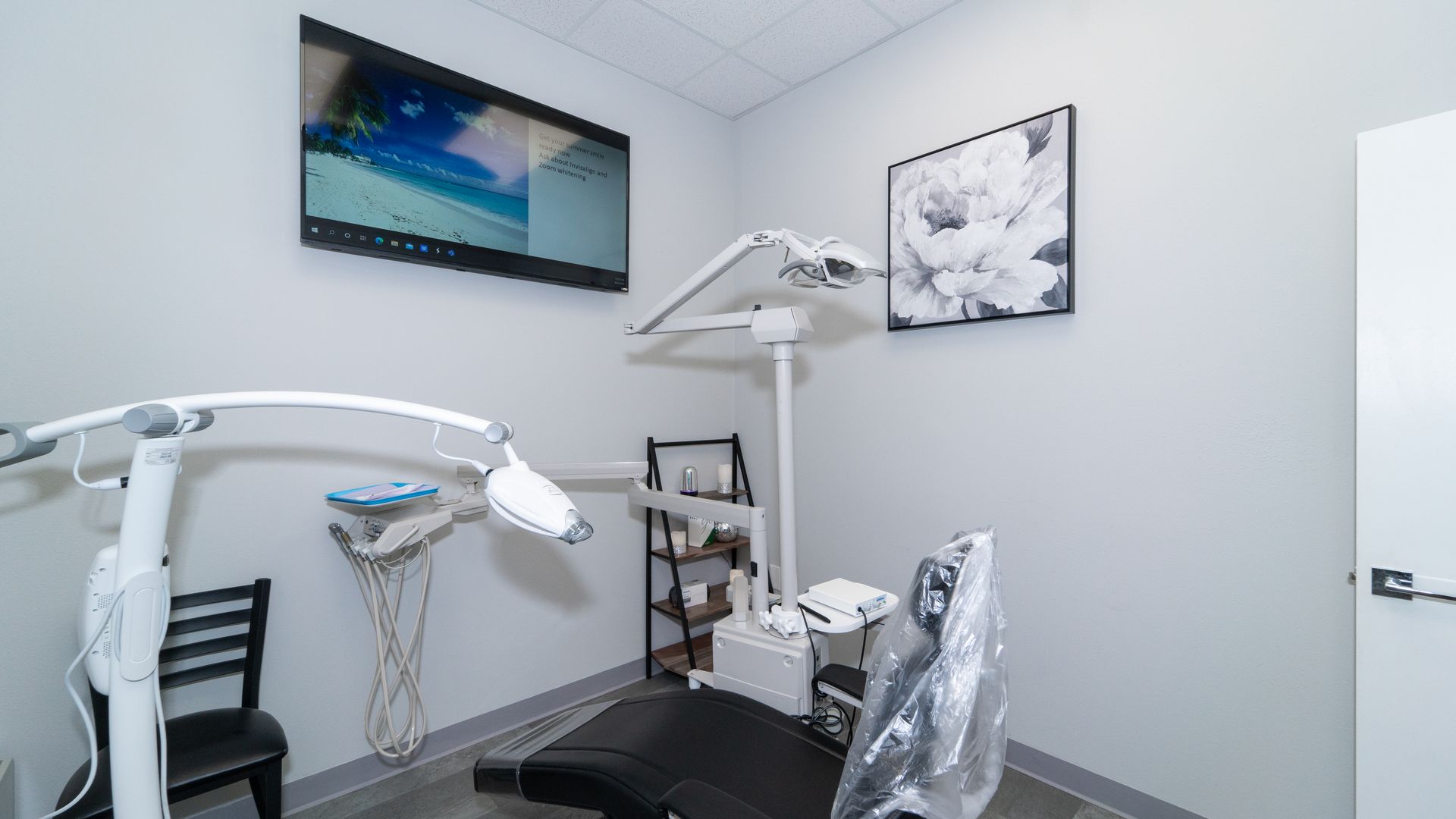 A dental office with a dental chair and a television on the wall.