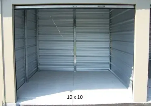 Empty 10x10 metal storage unit with an open door. Beige frame, light gray walls, concrete floor.