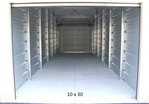 Interior of a 10x30 storage unit. Empty, gray walls and floor, metal structure.
