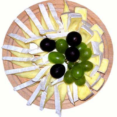 Formaggio e uva disposti su un piatto di legno.