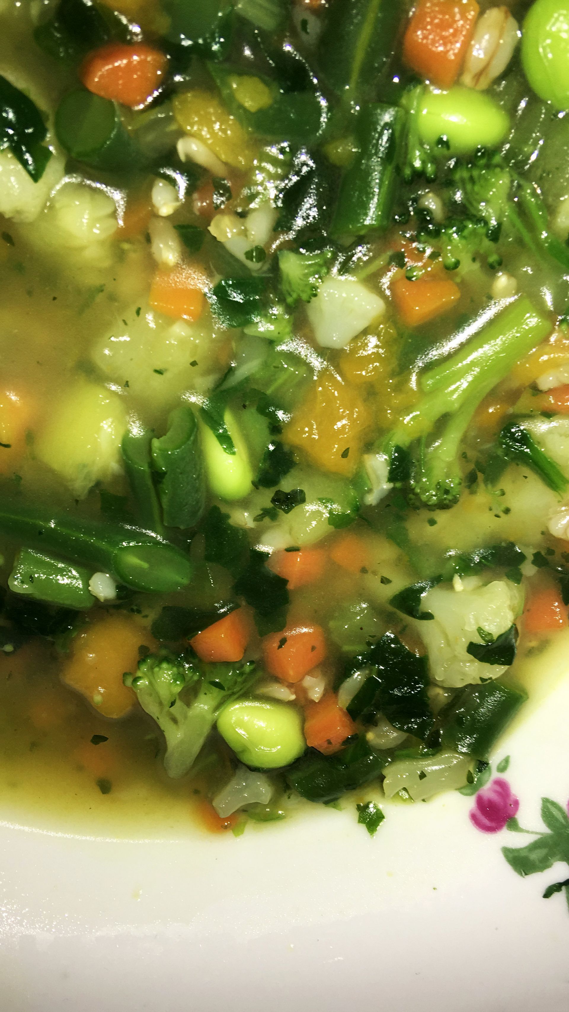 Zuppa di verdure in una ciotola bianca con fagiolini, carote ed edamame ben visibili.