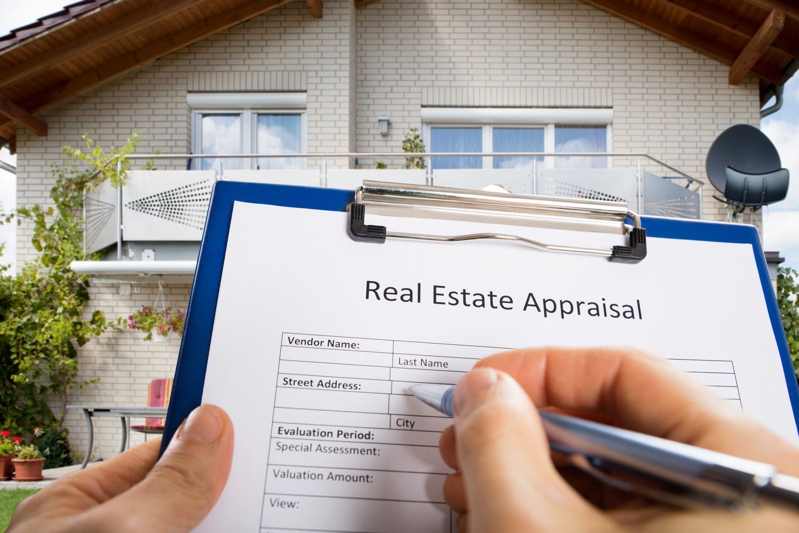 A person is holding a clipboard with a real estate appraisal on it in front of a house.