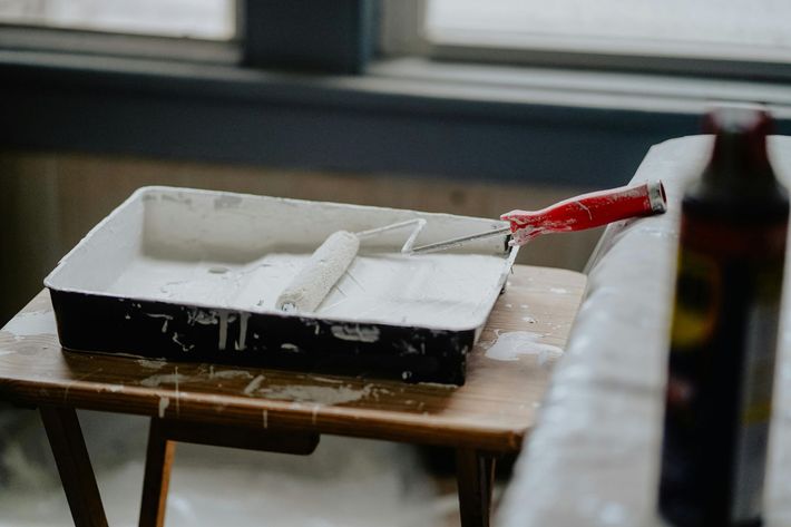 Red paint roller on a table beside a white foam tray in a classroom-like setting