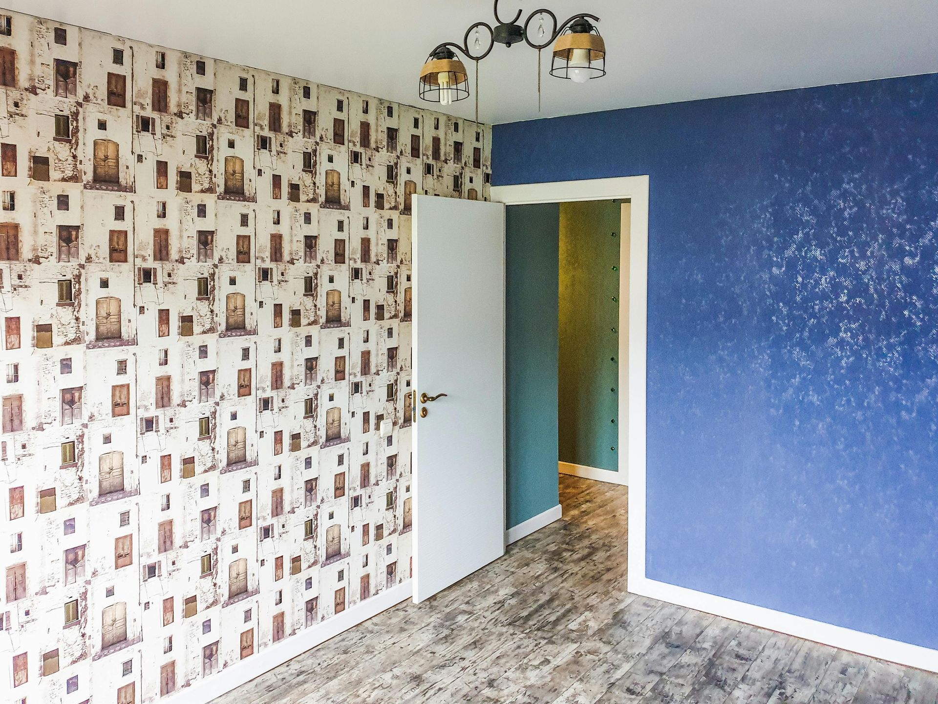Empty room with blue and patterned walls, open door, and ceiling light fixture