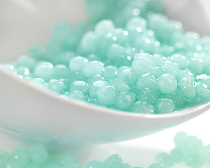 a close up of a bowl of blue beads on a table .