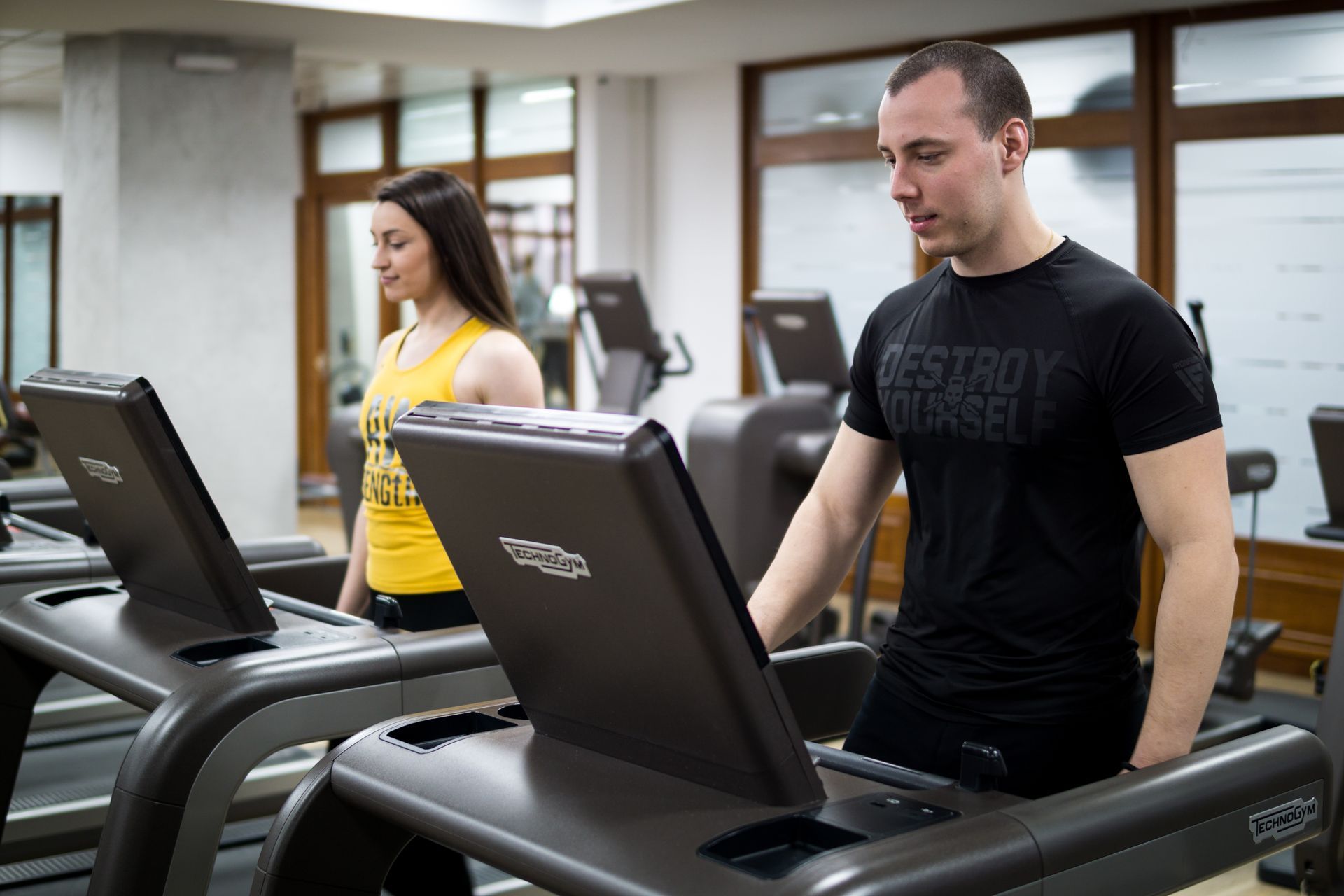 a man and a woman are running on treadmills in a gym .