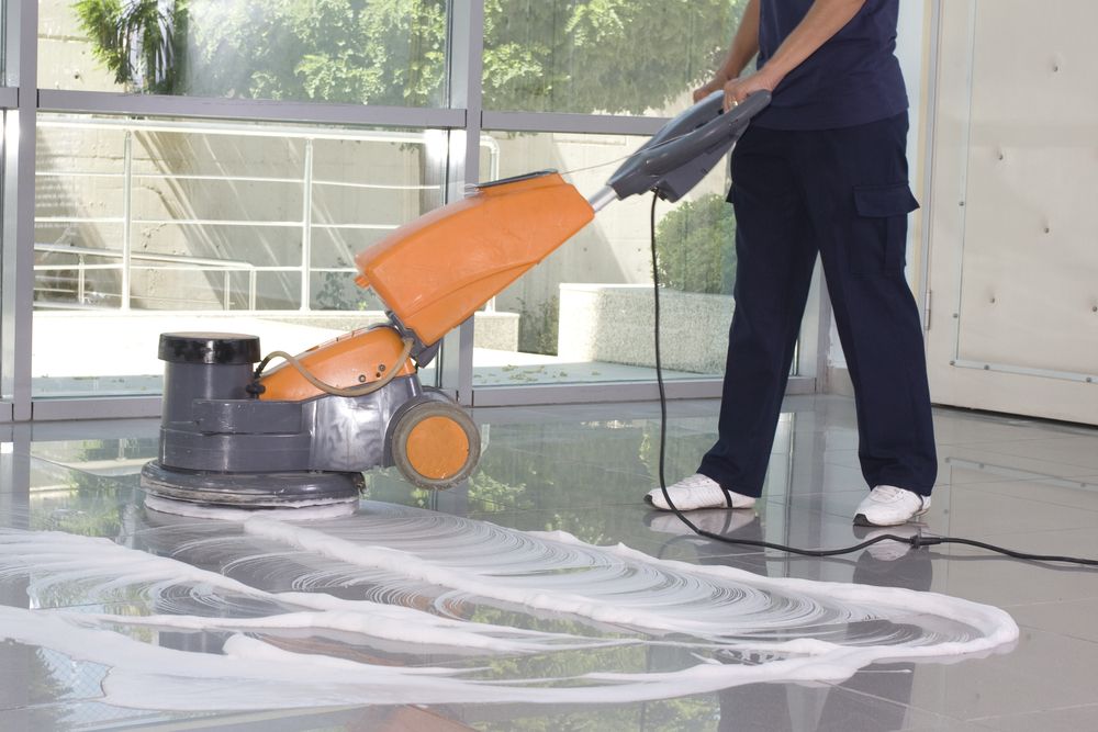A Woman is Cleaning a Floor With a Machine — Bali Green Cleaners in Winnellie, NT