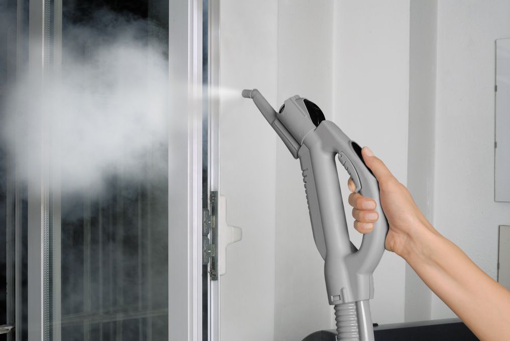 A Person is Using a Steam Cleaner to Clean a Window — Bali Green Cleaners in Winnellie, NT