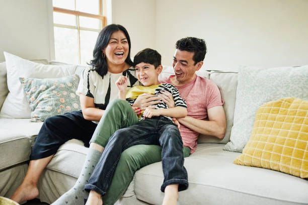 A family is sitting on a couch laughing together.