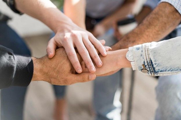 A group of people are putting their hands together in a circle.