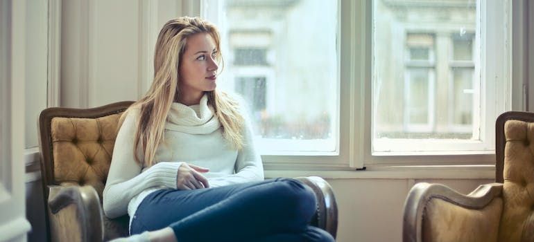 A woman is sitting in a chair in front of a window.