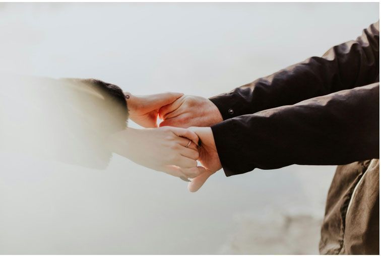 A man and a woman are holding hands and looking at each other 's wrists.